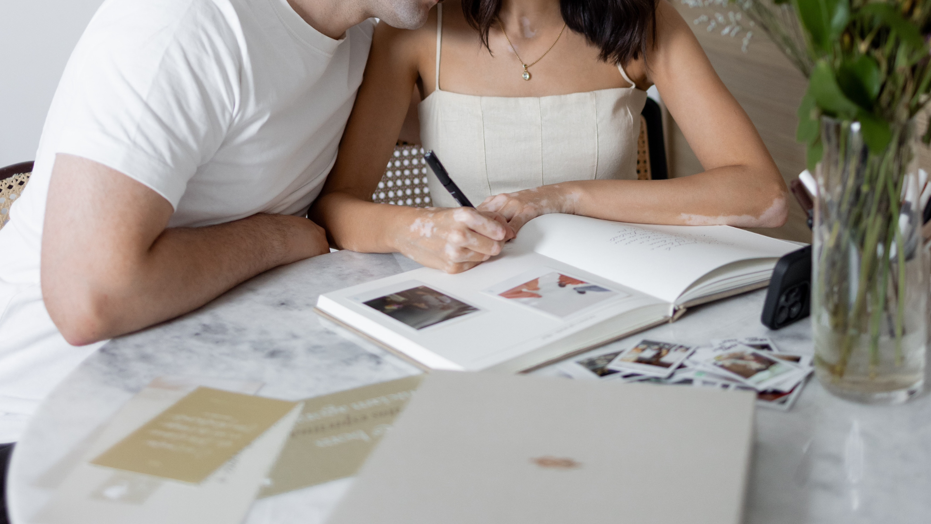 Casal preenchendo album de casamento juntos